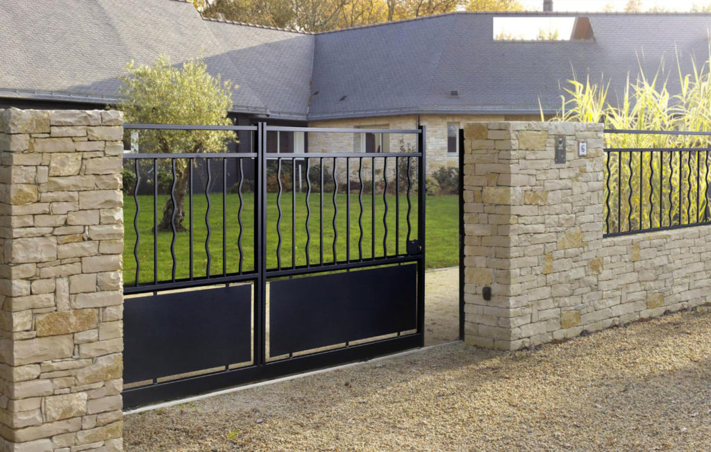 extérieur d'une maison en pierre avec un portail coulissant noir
