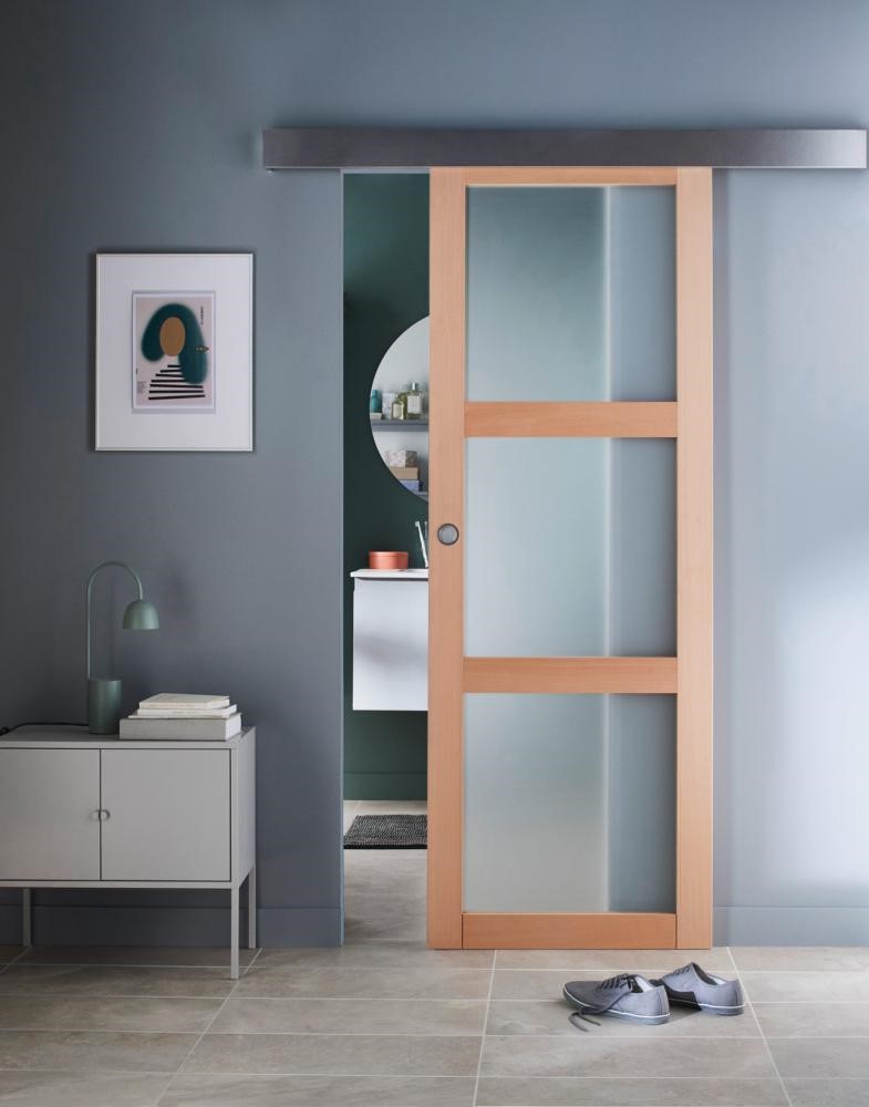 salon design avec petit meuble en fer et porte coulissant en bois et en verre