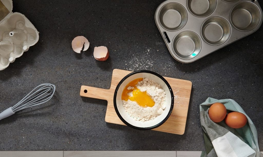 Vu de dessus, plan de travail en résine grise avec posé dessus des ingrédients pour préparer un gâteau.