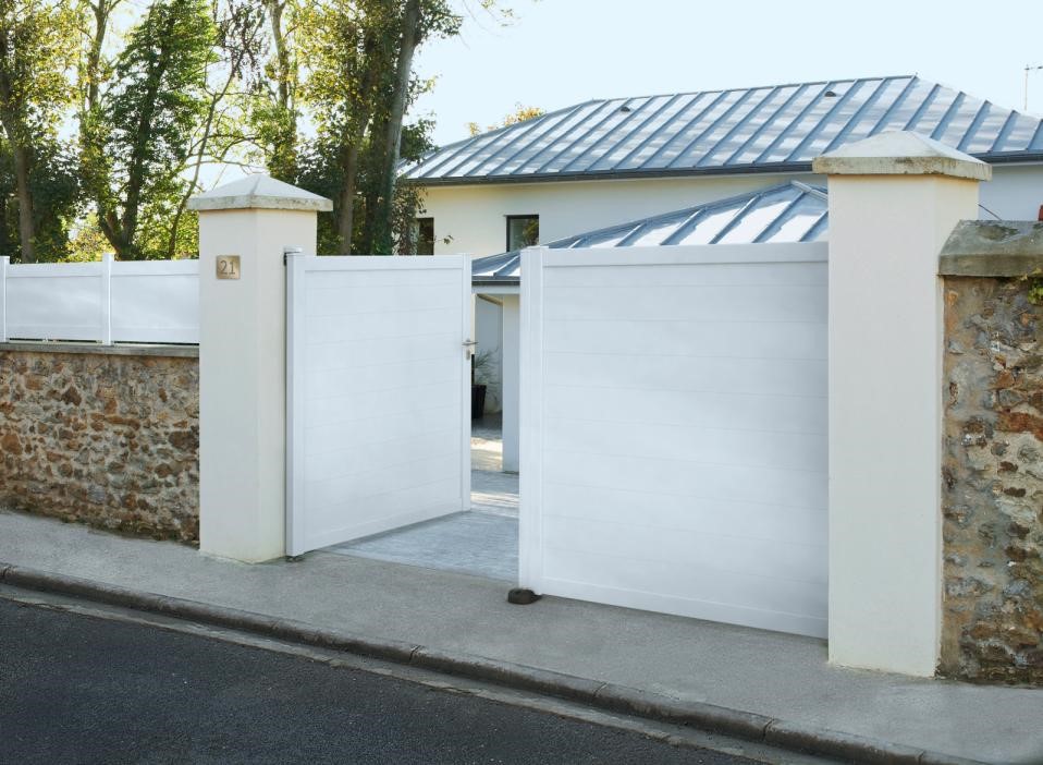 Portail battant blanc ouvert de moitié devant une maison